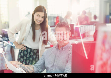 Portrait smiling fashion designers reviewing paperwork in office Stock Photo