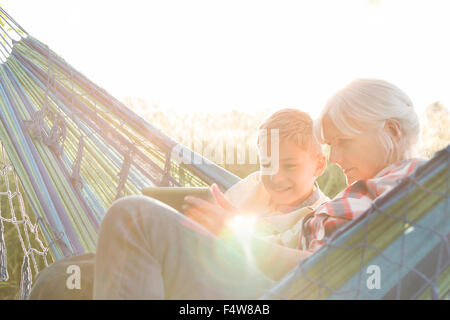 Grandmother and grandson using digital tablet in sunny hammock Stock Photo