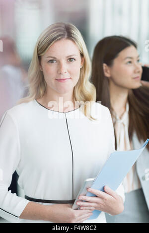 Portrait confident businesswoman with folder and digital tablet Stock Photo