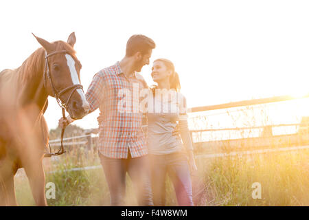 Affectionate couple walking with horse in rural pasture Stock Photo