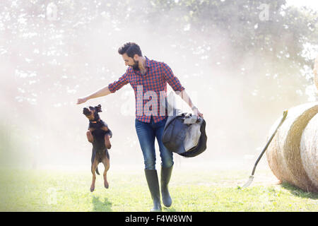 Man with saddle walking with jumping dog Stock Photo