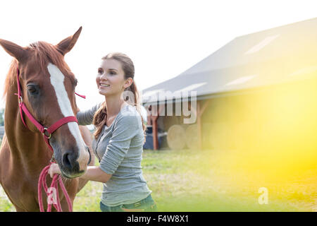 Smiling woman with horse outside rural barn Stock Photo