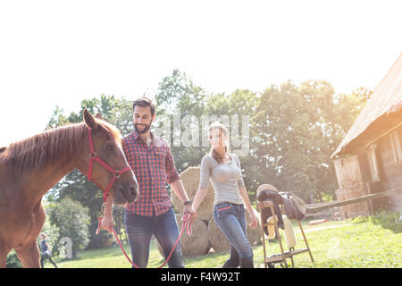 Couple walking horse outside rural barn Stock Photo