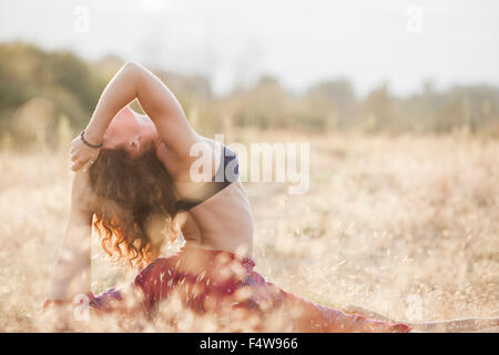 Woman in royal king pigeon yoga pose in rural field Stock Photo