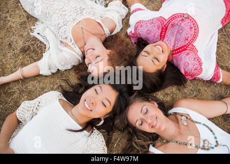 Overhead view of smiling boho women laying in circle with eyes closed Stock Photo