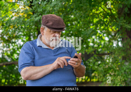 Portrait of bearded senior man using cellular phone outdoor Stock Photo