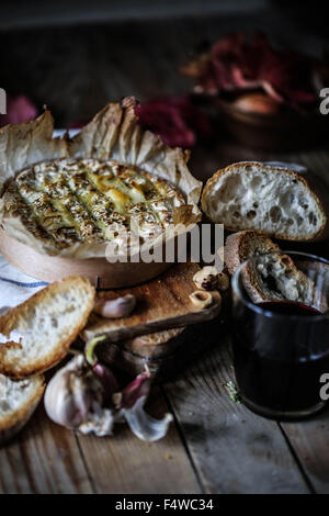 Baked Coulommiers cheese and garlic bread on a wooden, rustic table. Stock Photo