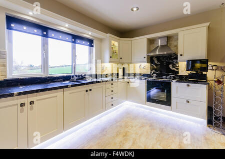 Modern kitchen with white units and under-unit lighting. Stock Photo