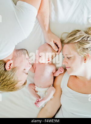 Baby boy (0-1 months) with his parents on bed