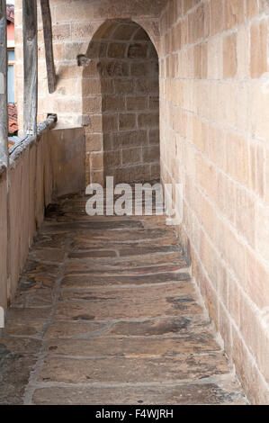 Narrow passage cobblestoned with archs outside the church of St. Nicholas in Orio. Basque Country. Stock Photo