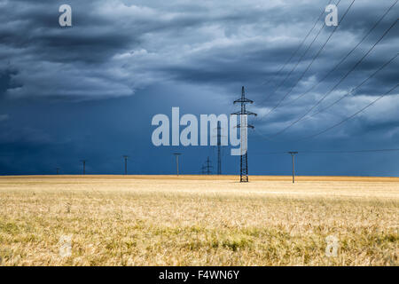 Huge thundercloud over a wheat field and electric pylons in the distance, Czech Republic Stock Photo