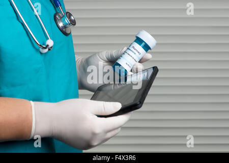 Nurse checks prescription bottle using tablet computer. Stock Photo