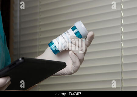 Nurse checks prescription bottle using tablet computer. Stock Photo