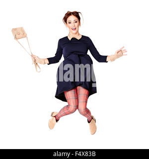 Young woman in dark blue dress and checkered tights is jumping over white background. Stock Photo
