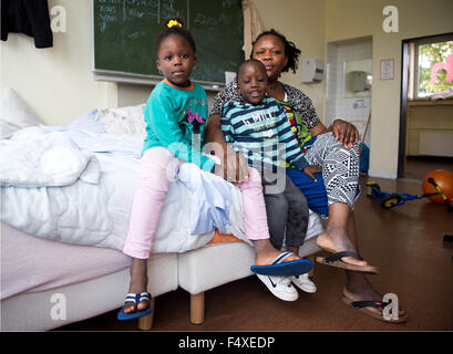 Duesseldorf, Germany. 22nd Oct, 2015. Evbuomwan Zoreth from Nigeria sits with her children Silvia (6) and David (5) on a bed in a refugee shelter in Duesseldorf, Germany, 22 October 2015. Photo: Monika Skolimowska/dpa/Alamy Live News Stock Photo