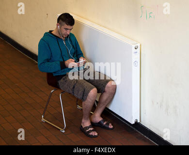 Duesseldorf, Germany. 22nd Oct, 2015. Jalal Piso from Syria sits on a chair next to the heating, in the refugee shelter in Borbecker Strasse in Duesseldorf, Germany, 22 October 2015. Photo: Monika Skolimowska/dpa/Alamy Live News Stock Photo