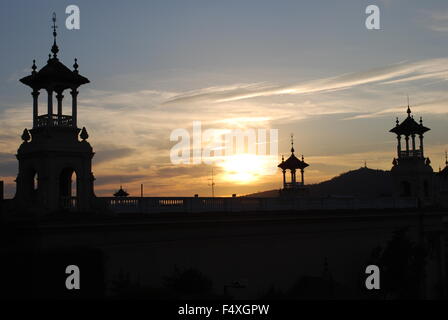 Sunset at The National Art Museum of Catalonia in Barcelona. Towers and statues appear in silhouette against the setting sun. Stock Photo