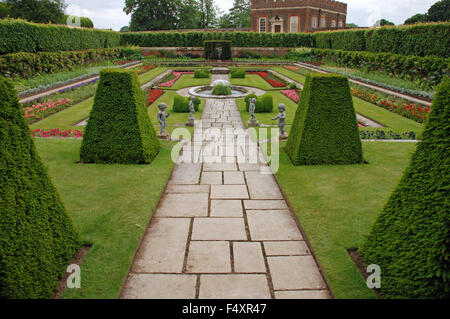 Formal symmetrical gardens trimmed hedge topiary stone rock path and sculptures at Hampton Court Palace, London, England Stock Photo