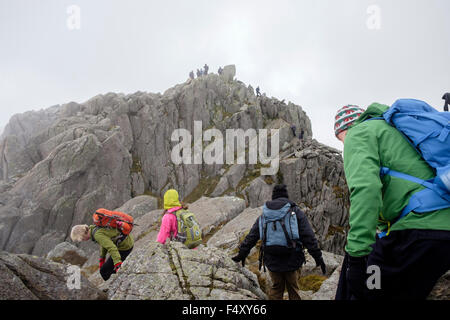 Hikers scrambling up to Mount Tryfan rocky summit in low cloud in mountains of Snowdonia National Park. Ogwen, North Wales, UK Stock Photo