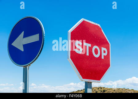 Stop sign and signal direction compulsory against the sky in Spain Stock Photo
