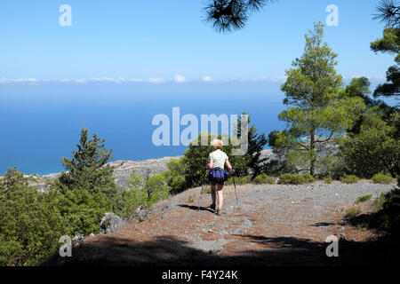 Back view of woman backpack & water bottles walking alone hiking on a September day looking out to sea on the coast of Northern Cyprus  KATHY DEWITT Stock Photo