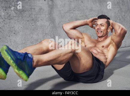 Muscular male fitness athlete doing sit ups, Clean look on grey background, visible no shirt Stock Photo