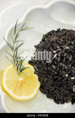 Black risotto and squid on the plate with lemon Stock Photo