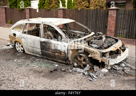 Burnt car in arson fire, white car wreck at the pavement in Poland, spoilt empty car in fire accident, charred vehicle junk and Stock Photo