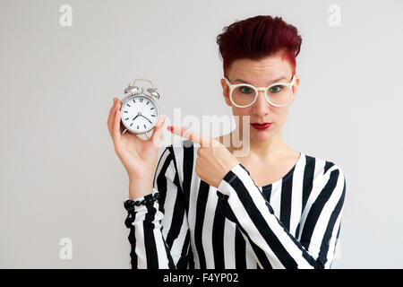 red-haired woman holding alarm clock and yawns Stock Photo - Alamy