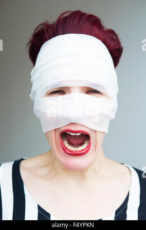 beautiful woman with red hair wrapped in bandages is screaming Stock Photo