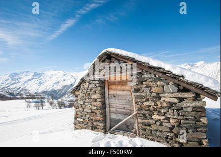 Remote stone mountain hut on an alpine slope covered in snow Stock Photo