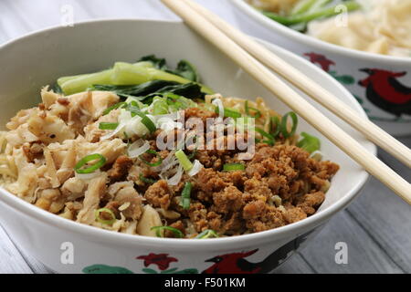 Noodle soup with diced chicken, minced pork, and green vegetable. Served in ceramic bowl with rooster print. Stock Photo