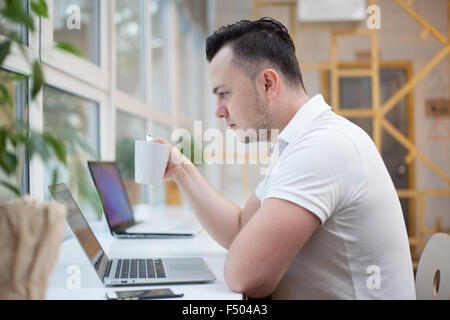 Man using laptop in white office Stock Photo