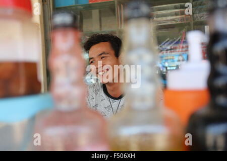 Young smiling Asian man behind bottles. Stock Photo