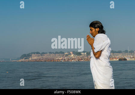 Priest praying at the river Ganges, the crowded Sangam, the confluence of the rivers Ganges, Yamuna and Saraswati, at Kumbha Mel Stock Photo