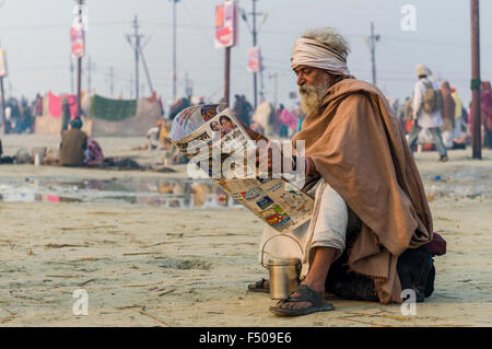 Pilgrim reading newspaper in the morning at the Sangam, the confluence of the rivers Ganges, Yamuna and Saraswati, at Kumbha Mel Stock Photo