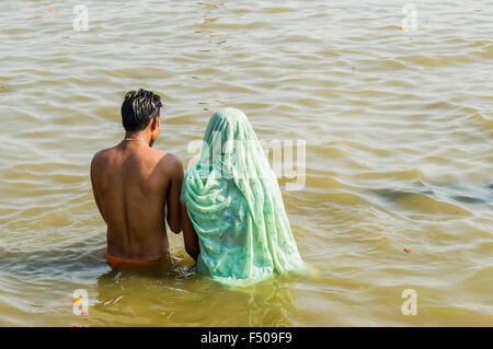 Young couple praying in the water of river Ganges early morning at the Sangam, the confluence of the rivers Ganges, Yamuna and S Stock Photo