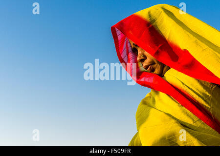 Portrait of a woman in yellow red sari at the Sangam, the confluence of the rivers Ganges, Yamuna and Saraswati, at Kumbha Mela Stock Photo