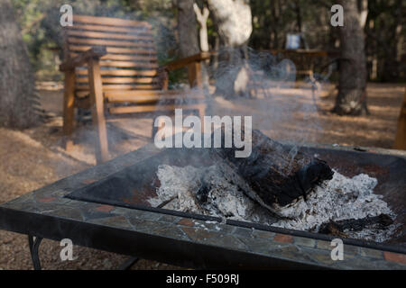An extinguished but still smoldering log burning fire at a campsite in Texas Stock Photo
