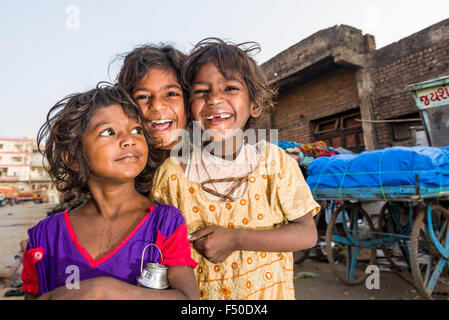 Portraits of three smiling street kids, children, who are living just beside busy roads on the pavement Stock Photo