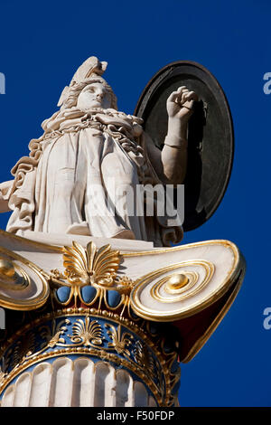 Closeup of the Greek goddess Athena holding a shield statue and ornamental pillar details against blue sky. Athens, GR Stock Photo