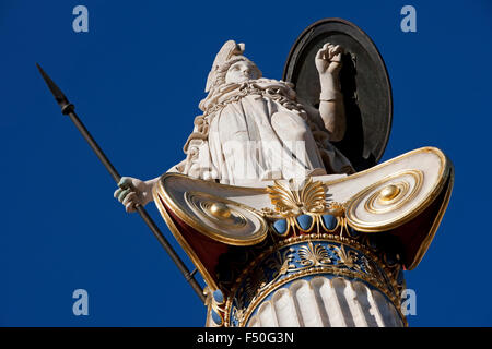 Close-up view of the Greek goddess Athena holding a shield and spear statue including ornamental pillar details. Athens, GR Stock Photo