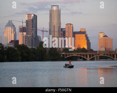 A man fishing at sunset on Lady Bird Lake in front of the Austin, Texas skyline Stock Photo