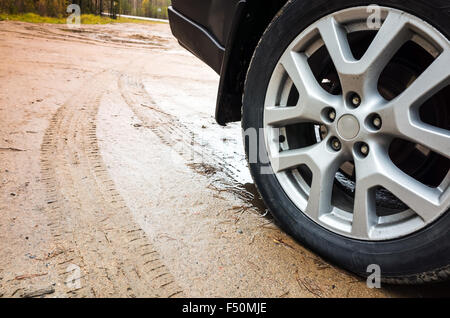 Car wheel with light alloy disc on dirty country road, close up photo Stock Photo