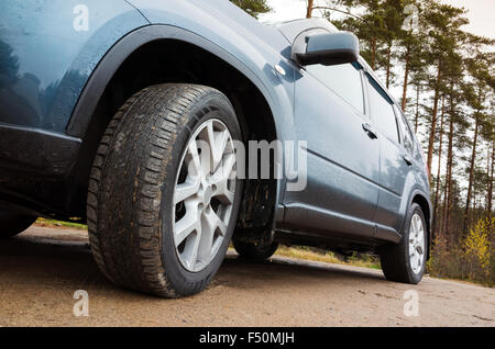 Closeup wide angle car fragment, wheel with light alloy disc on dirty country road Stock Photo