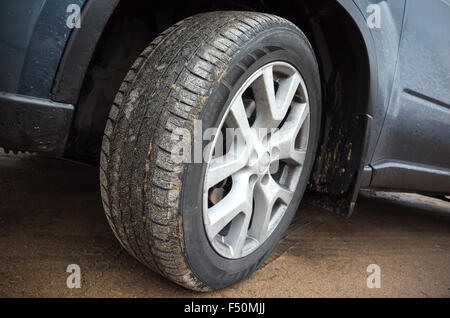 Automotive wheel with light alloy disc on dirty country road, closeup photo Stock Photo