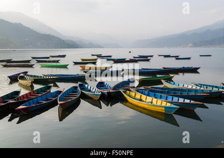 Colorful boats on Phewa Lake, hills and clouds in the back Stock Photo