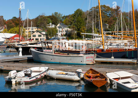 Dinghies line a dock in front of schooners and windjammers anchored in Camden harbor in Camden, Maine. Stock Photo