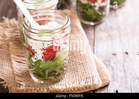 salad with tomatoes, green leafs and feta cheese in mason jars Stock Photo