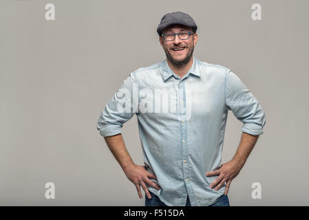 Friendly attractive man with glasses looking at the camera with a lovely warm smile, upper body over grey Stock Photo